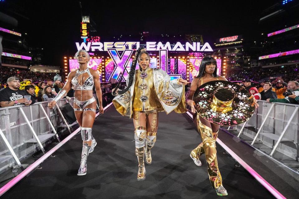 Jade Cargill, Bianca Belair, and Naomi, each in gold outfits, enter the ring during Night One of WrestleMania 40 at Lincoln Financial Field on April 6, 2024 in Philadelphia, Pennsylvania