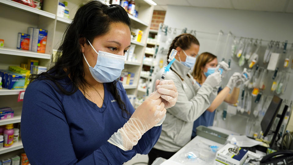 Pharmacist Claudia Corona-Guevara and registered nurses Amy Wells and Megan McLaughlin draw shots of Johnson &  Johnson's COVID-19 vaccine in a pharmacy