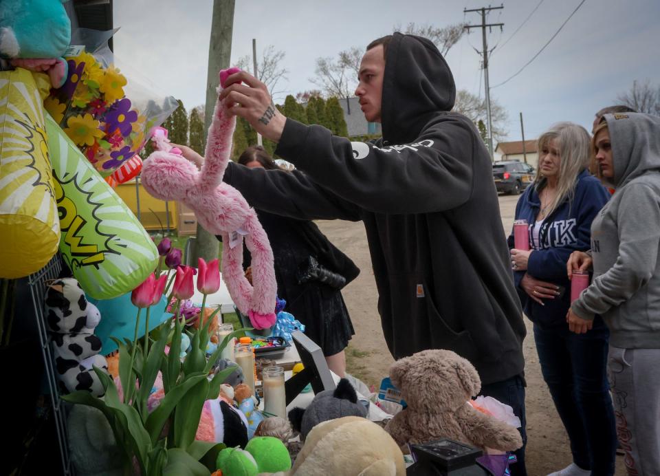 Nicholas Phillips places a stuffed animal at the memorial for Alayna and Zayn Phillips during a vigil held on Friday, April 26, 2024, at the Swan Boat Club in Newport.