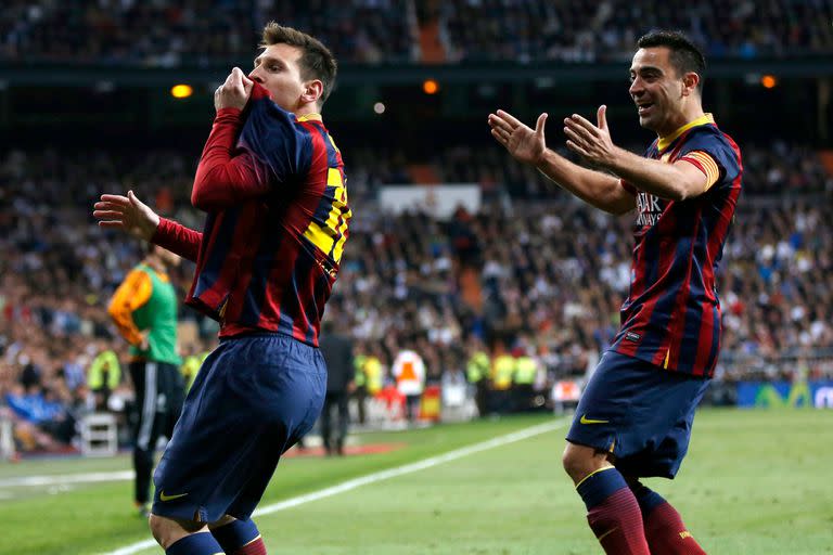 Lionel Messi de Barcelona (L) celebra con su compañero de equipo Xavi Hernández después de marcar un gol de penal contra el Real Madrid durante el segundo partido de fútbol Clásico de la Liga de la temporada en el estadio Santiago Bernabeu en Madrid el 23 de marzo de 2014.