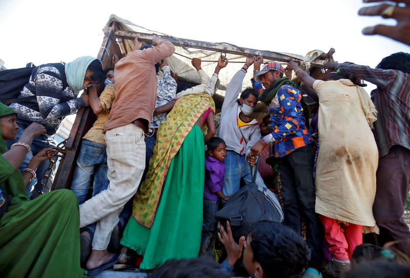 Trabajadores migrantes y sus familias abordan un camión para regresar a sus aldeas durante un cierre nacional de 21 días para limitar la propagación de la enfermedad por coronavirus (COVID-19), en Ahmedabad, India.