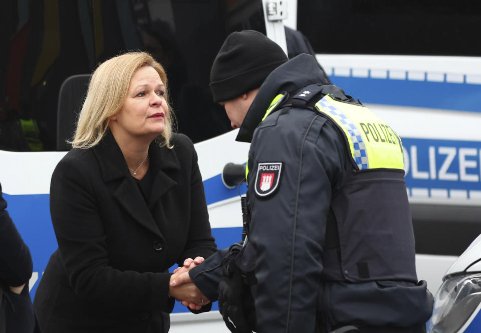 Germany's Interior Minister Nancy Faeser, left, shakes hands with a police officer at the site where several people were killed last night in a rampage during a Jehovah's Witness event, in Hamburg, Germany, Friday March 10, 2023. (Christian Charisius/dpa via AP)