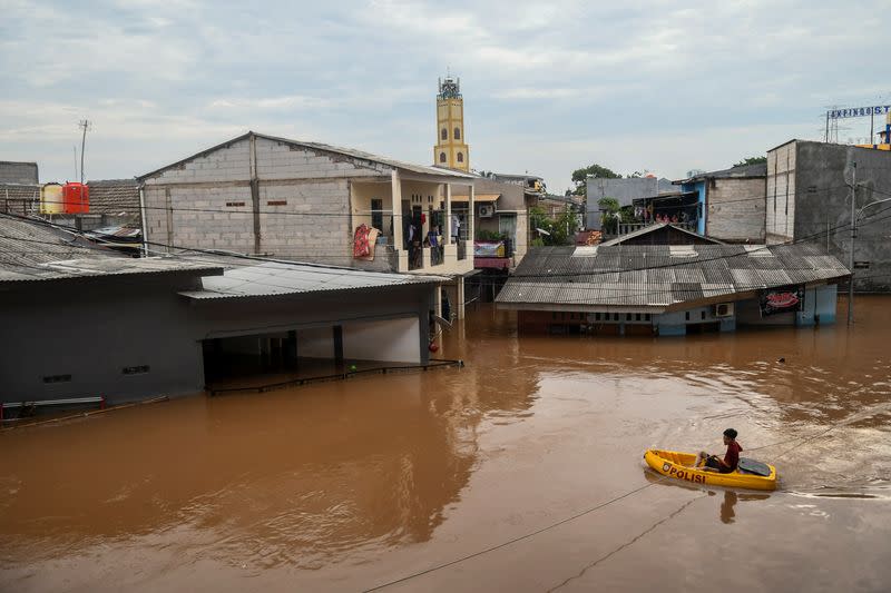 A man uses an inflatable boat as floods hit in Jakarta, Indonesia