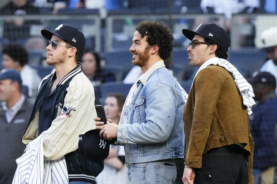 Nick, Kevin, and Joe, right of the Jonas Brothers react to a video presentation before a baseball game between the New York Yankees and the Philadelphia Phillies Tuesday, April 4, 2023, in New York. The Jonas Brothers will perform Saturday, Aug. 1, 2023 at Yankee Stadium. (AP Photo/Frank Franklin II)