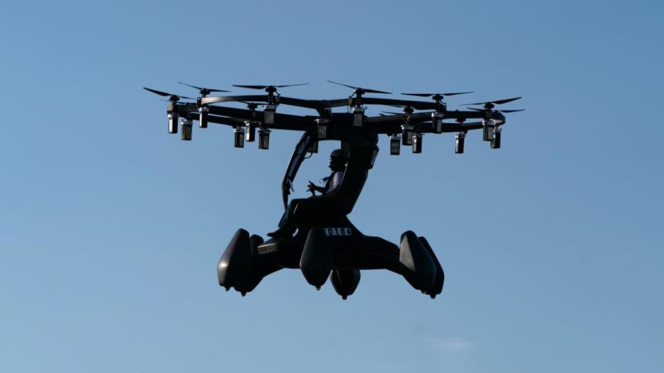 A flying car photographed in the air against a bright blue sky in Tokyo, Japan.