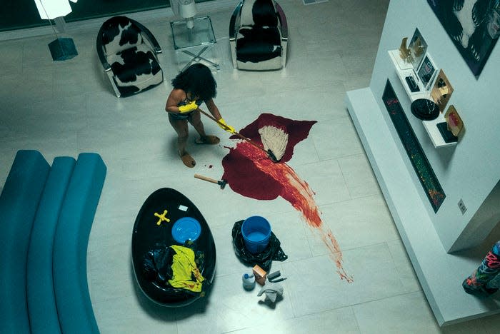 Dre (Dominique Fishback) mops up blood in a sleek white living room in this still from "Swarm."