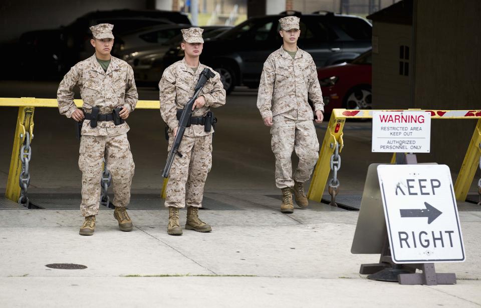 Members of the United States Marine Corps maintain a watch on their barracks as police respond to a shooting at the Washington Navy Yard, in Washington September 16, 2013. A gunman shot five people at the U.S. Navy Yard on Monday, including two law enforcement officers, and the shooter was being sought in a building housing the Naval Sea Systems Command headquarters, officials said. (REUTERS/Joshua Roberts)