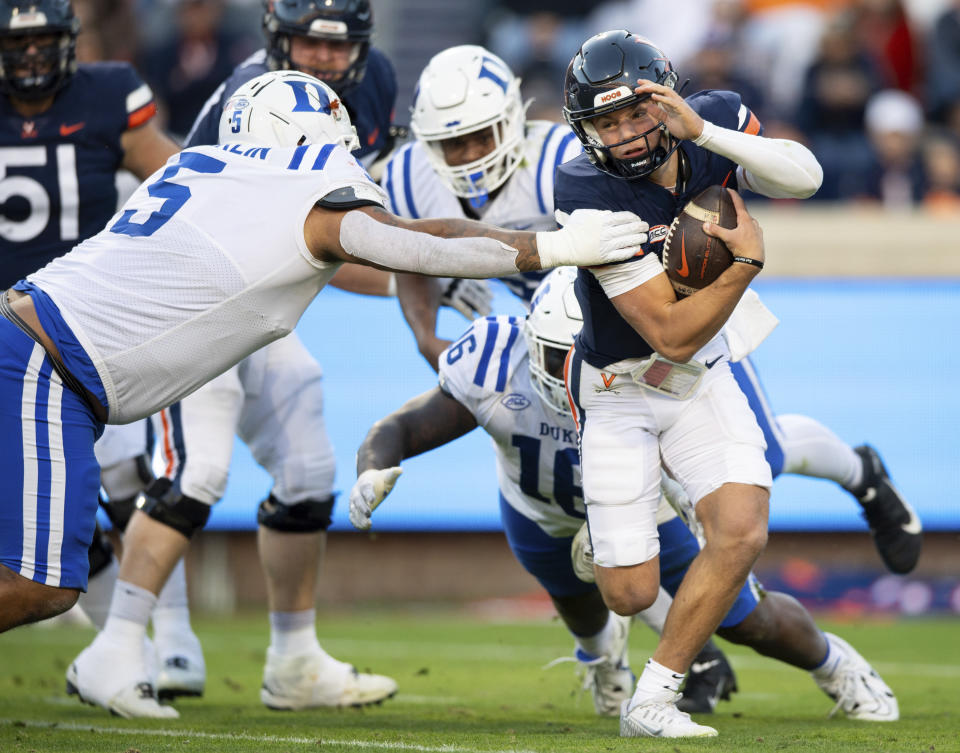 Virginia quarterback Anthony Colandrea, right, is sacked by Duke defensive tackles Ja'Mion Franklin (5) and Aeneas Peebles (16) during the first half of an NCAA college football game Saturday, Nov. 18, 2023, in Charlottesville, Va. (AP Photo/Mike Caudill)