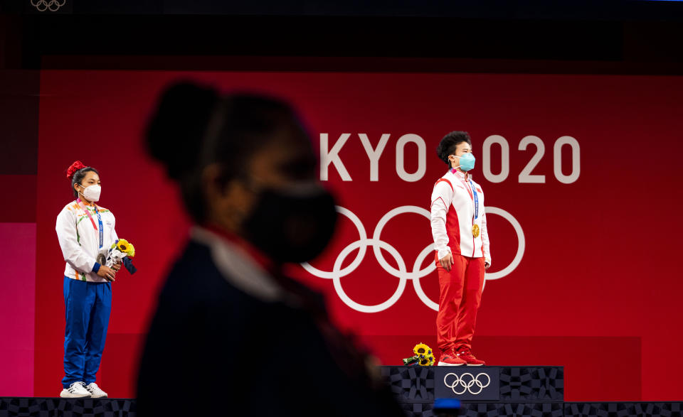 La levantadora de pesas Hou Zhihui de China, a la derecha, recibe la medalla de oro en la división femenil de 49 kilogramos en los Juegos Olímpicos de Tokio, el 24 de julio de 2021. (Doug Mills/The New York Times)