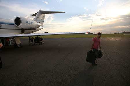 A staff member for Republican presidential candidate Donald Trump loads luggage onto a media bus in Charlotte, North Carolina, U.S., August 17, 2016. REUTERS/Carlo Allegri