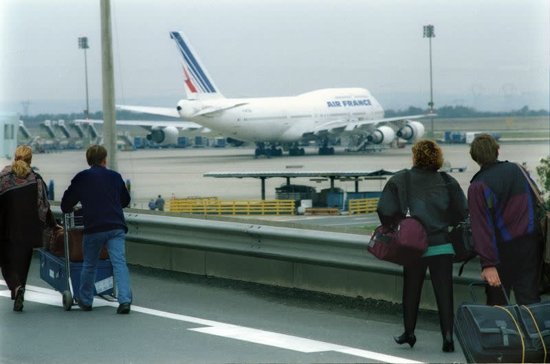 FILE PHOTO: Passengers at Paris's Charles de Gaulle (Roissy) airport pull their baggage along a ramp in front of..
