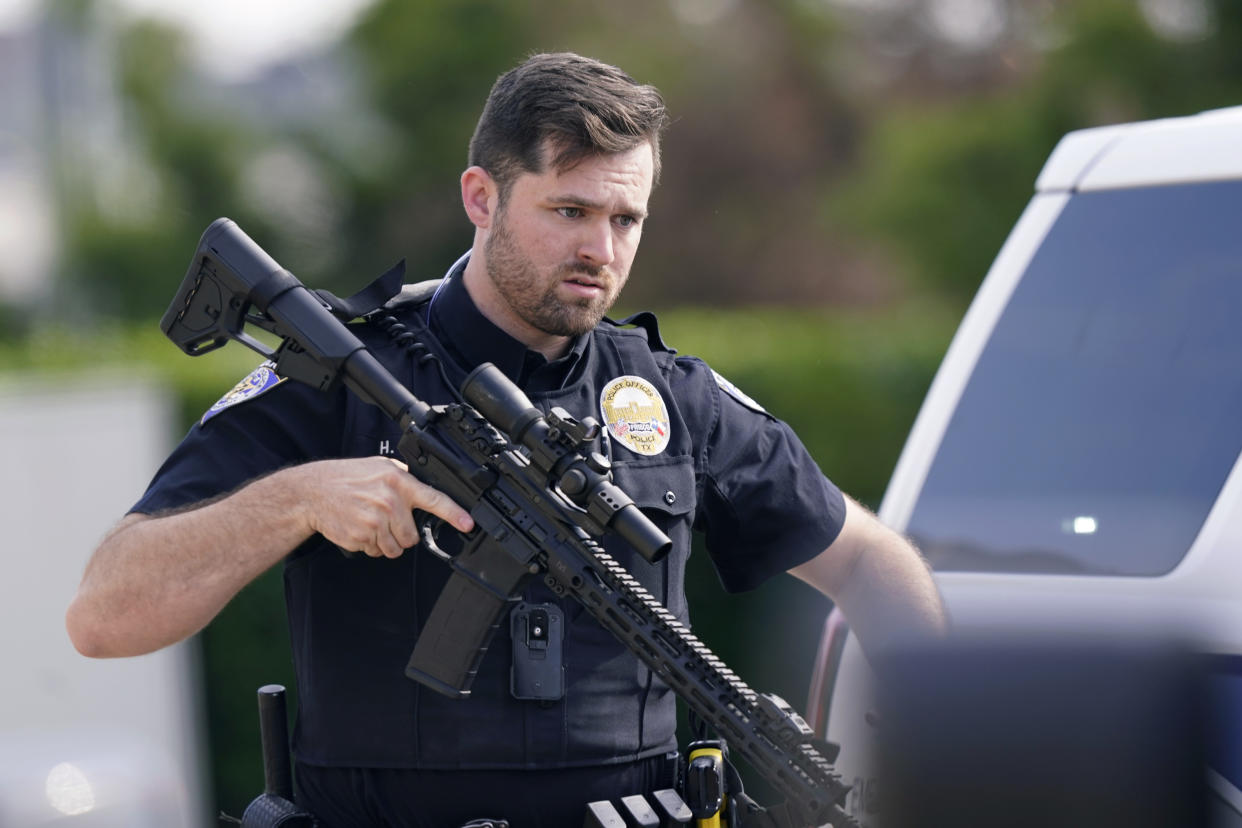 A law enforcement officer carries a rifle as people are evacuated from a shopping center where a shooting occurred Saturday, May 6, 2023, in Allen, Texas. (AP Photo/LM Otero)