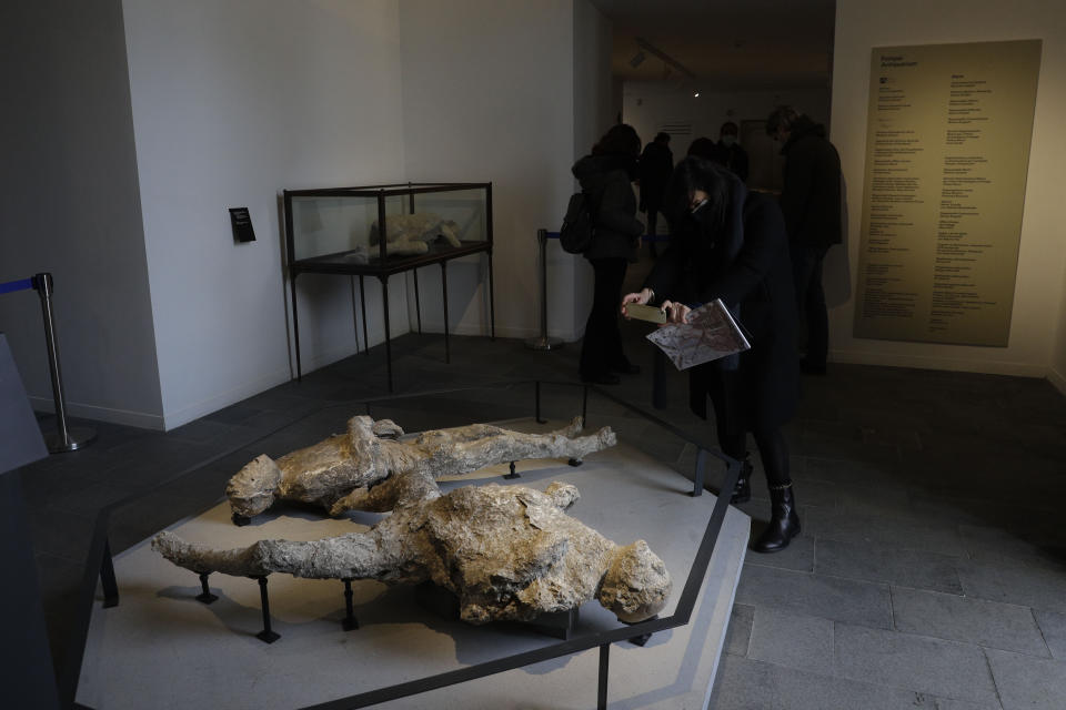 Una mujer fotografía las piezas fundidas de dos víctimas de la erupción del volcán Vesubio del 49 D.C. en el recién reabierto Antiquario en Pompeya, Italia, el lunes 25 de enero del 2021. Décadas después de haber sufrido daños en bombardeos y un terremoto, el museo de Pompeya renace para exponer los exquisitos hallazgos de las excavaciones en la antigua ciudad romana. (AP Foto/Gregorio Borgia)