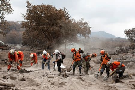 Rescue workers search the house of one of Eufemia Garcia's missing sisters in an area affected by the Fuego volcano at San Miguel Los Lotes in Escuintla, Guatemala, June 14, 2018. REUTERS/Carlos Jasso