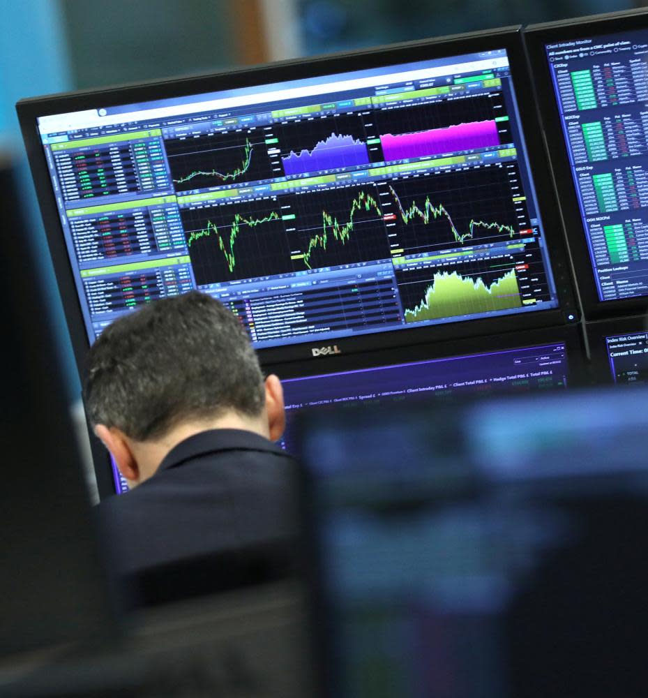 A trader works as screens show market data in London, Britain