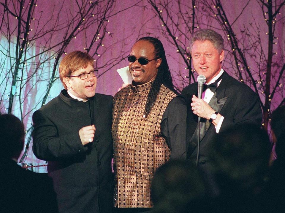 US president Bill Clinton thanks Elton John and Stevie Wonder after they performed at an official dinner in honour of Tony Blair in February 1998 (AFP via Getty)