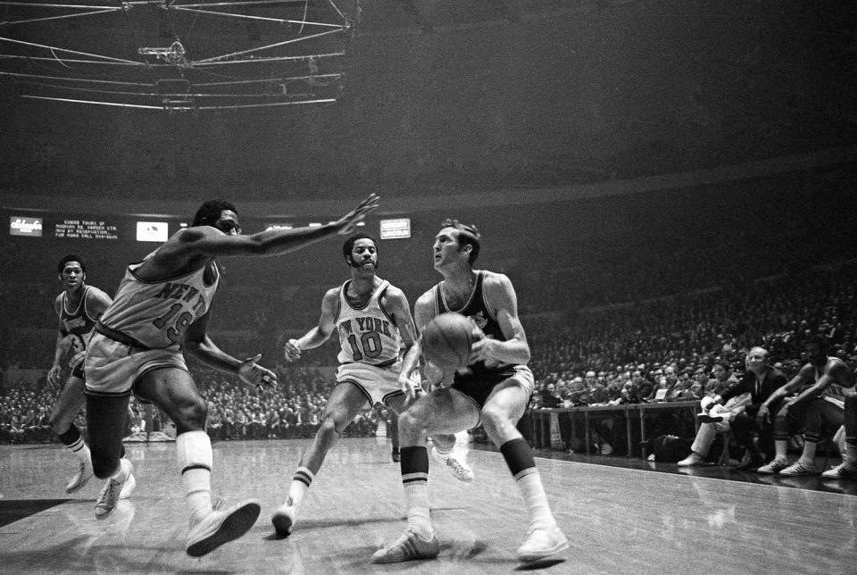 Jerry West of the Los Angeles Lakers crashes against Willis Reed of the New York Knicks as he passes off to Wilt Chamberlain in the opening minutes of the first game of the NBA Championship playoff series in Inglewood, Cal., on May 1, 1973.  (Jeff Robbins / AP file)