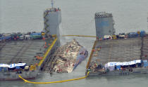 Workers prepare to lift the sunken Sewol ferry, center, in waters off Jindo, South Korea, Thursday, March 23, 2017. The 6,800-ton South Korean ferry emerged from the water on Thursday, nearly three years after it capsized and sank into violent seas off the country's southwestern coast, an emotional moment for the country that continues to search for closure to one of its deadliest disasters ever. (Park Gyung-woo/Hankookilbo via AP)