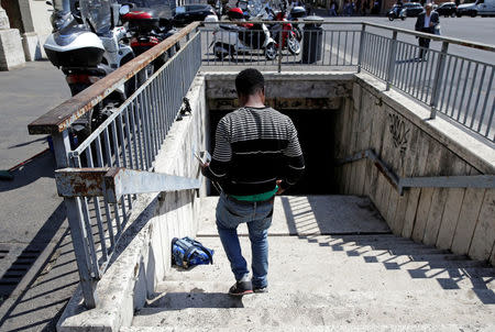 Christian Okoro of Nigeria collects his stuffs after sweeping a street in downtown Rome, Italy, May 18, 2017. Picture taken May 18, 2017. REUTERS/Max Rossi