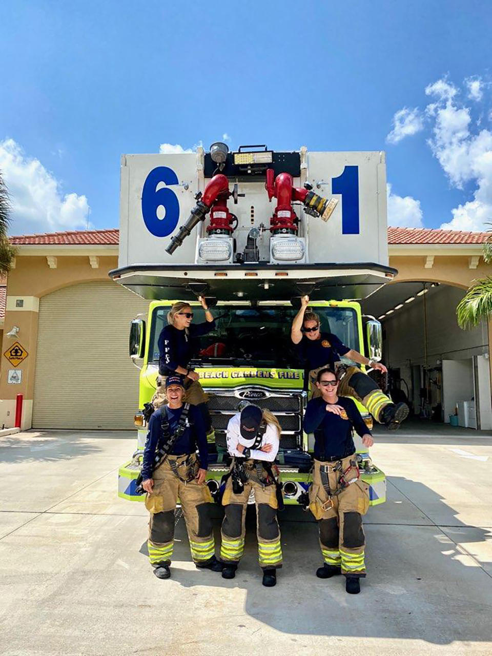 In this September 2020 photo provided by Palm Beach Gardens Fire and Rescue, firefighters lieutenant Kelsey Krzywada and Driver Engineer Sandi Ladewski (Sitting opposite on the truck), Lieutenant Krystyna Krakowski, fire medic Julie Dudley and Lieutenant (Acting Captain) Monica Marzullo (standing in front of the truck) pose at their station in Palm Beach Gardens, Fla. (Kodi Cabral/Courtesy of Palm Beach Gardens Fire and Rescue via AP)