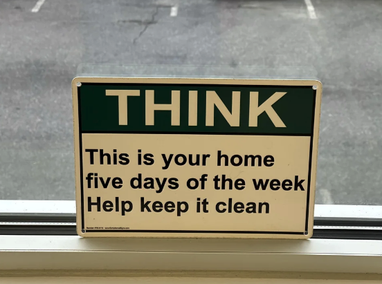 Sign reading: "THINK This is your home five days of the week Help keep it clean" placed on a window sill