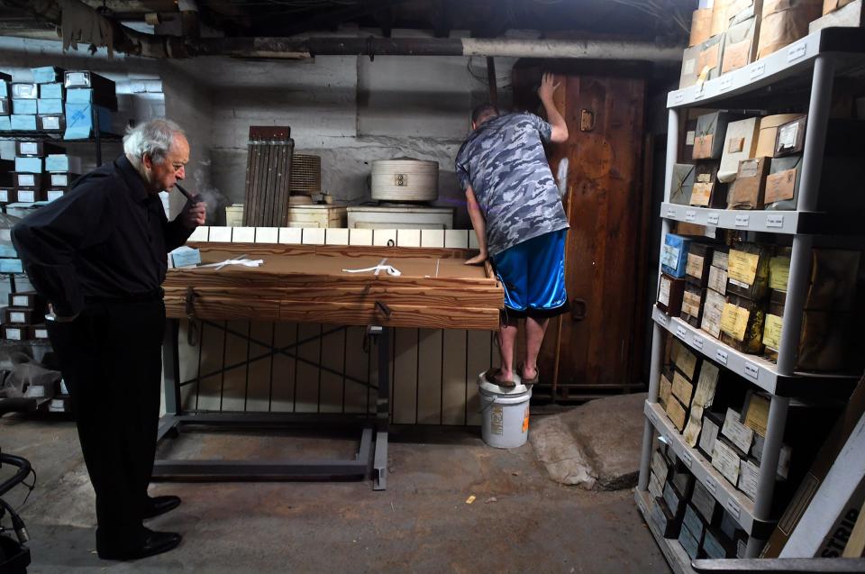 At Graham, Putnam & Mahoney Funeral Home owner Peter Stefan, left, and his assistant Dwayne Noyes look through unclaimed cremains in the basement.