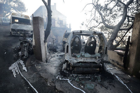 Vehicles that were destroyed by a burning wildfire are seen near a damaged home in Carros, near Nice, France. REUTERS/Eric Gaillard