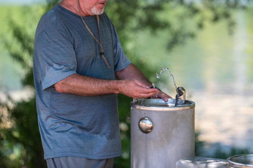 A resident tests the temperature of drinking fountain water during a heat wave.  / Credit: Sergio Flores via Getty Images