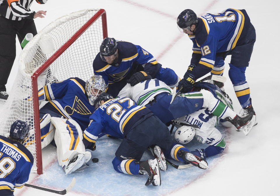 St. Louis Blues goalie Jordan Binnington (50) makes the save as players scramble in the crease against the Vancouver Canucks during the first period of an NHL hockey Stanley Cup first-round playoff series, Friday, Aug. 14, 2020, in Edmonton, Alberta. (Jason Franson/The Canadian Press via AP)