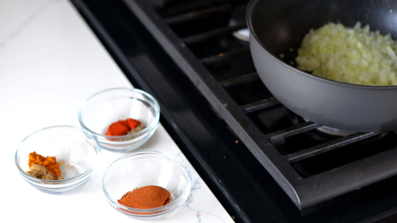 onion sauteeing near prepped spices