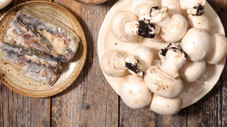 plates of raw mushrooms and canned sardines