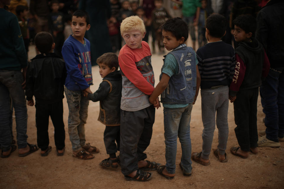 Syrian children hold hands as they wait for toys to be donated in a refugee camp for displaced people run by the Turkish Red Crescent in Sarmada district, on the outskirts north of Idlib, Syria, Friday, Nov. 26, 2021. (AP Photo/Francisco Seco)