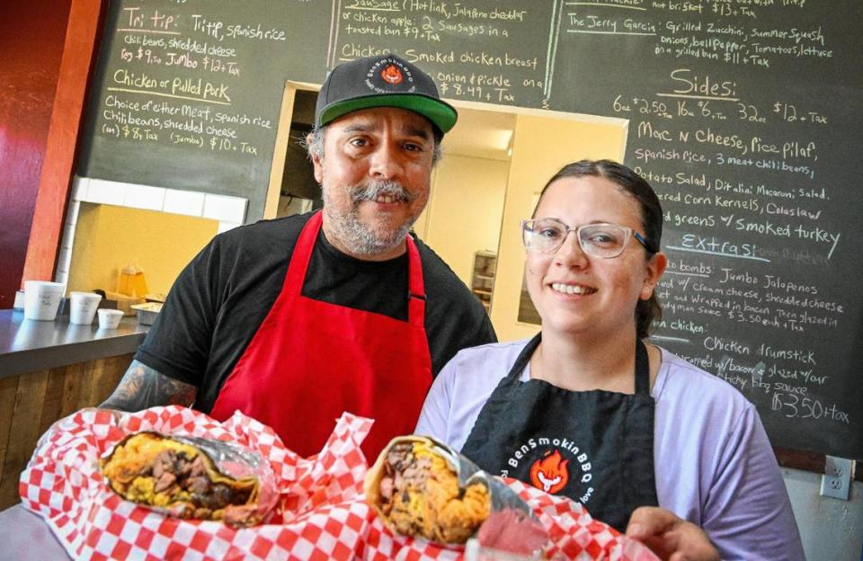 Chef Bernard Paul Mendoza III and his wife Rebecca hold up a Violin on Fire BBQ burrito with tri-tip, brisket, Spanish rice, Bernardo jalapeño bombs, chili beans and cheese at their restaurant, BenSmokin BBQ, in Fresno on Wednesday, July 12, 2023.