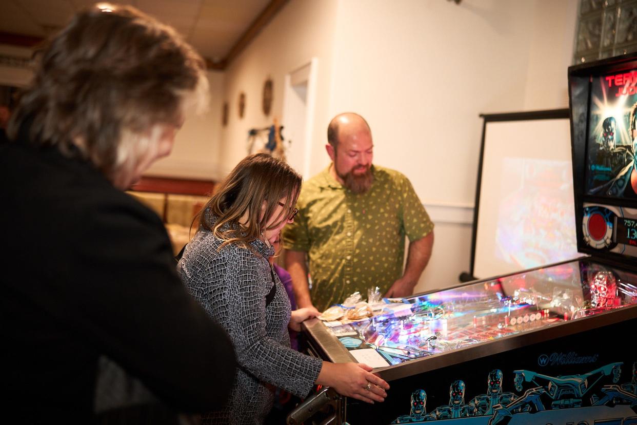 Margo Saulnier, left, director and creative strategist for the New Bedford Creative plays pinball with Chris Cardaci, right, who owns a Pinball Repair business.