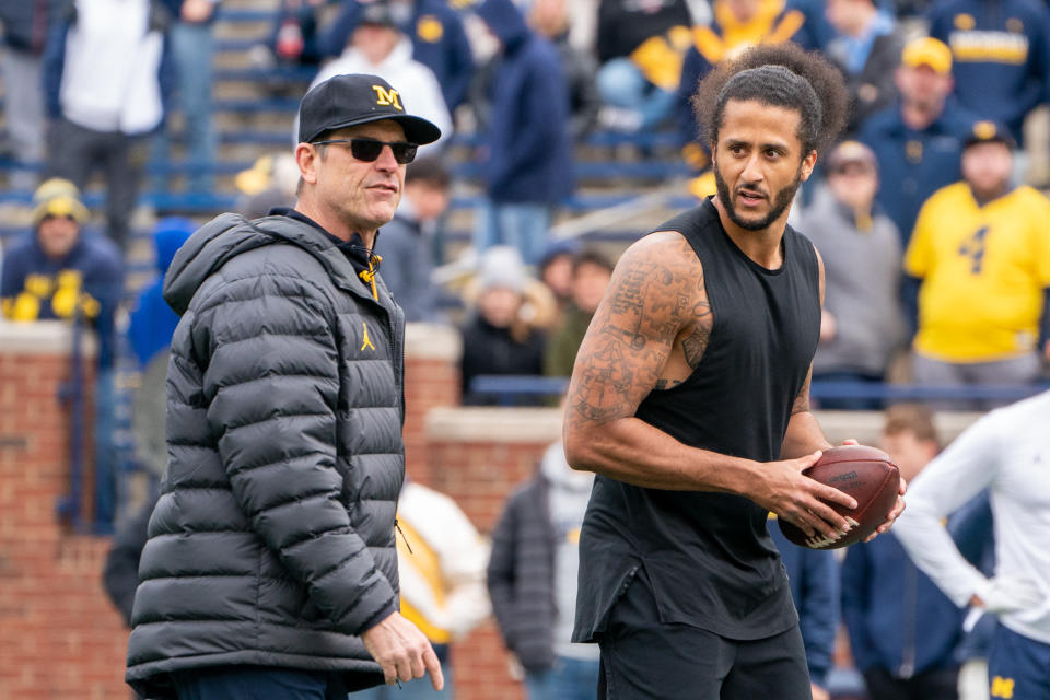 ANN ARBOR, MI - APRIL 02: Colin Kaepernick interacts with Michigan Wolverine head coach Jim Harbaugh during a pitching exhibition during halftime of the Michigan spring football game at Michigan Stadium on April 2, 2022 in Ann Arbor, Michigan. (Photo by Jaime Crawford/Getty Images)