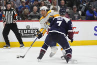 Nashville Predators left wing Kiefer Sherwood, back, launches a shot as Colorado Avalanche defenseman Devon Toews delivers a check in the second period of an NHL hockey game Saturday, March 30, 2024, in Denver. (AP Photo/David Zalubowski)