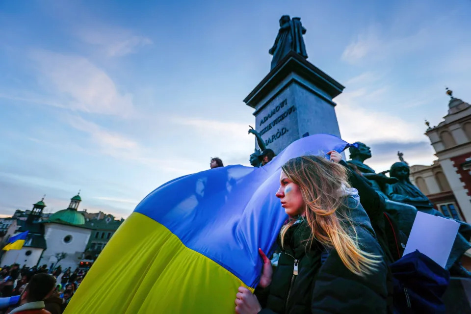 A protester holds a giant Ukrainian flag during a protest in response to the Russian invasion of Ukraine in Krakow, Poland.