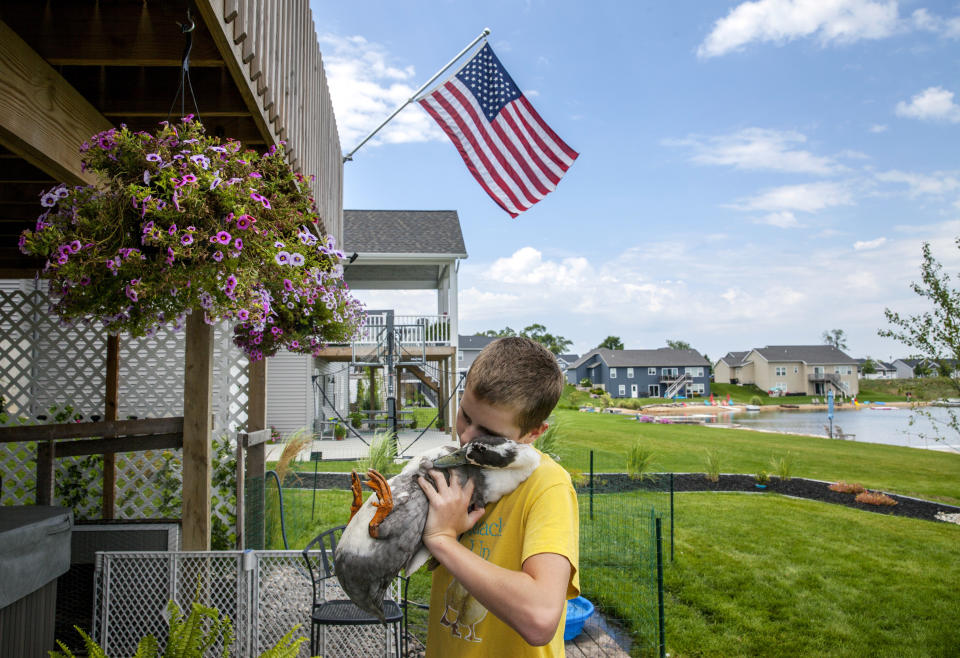 In this Thursday, Aug. 2, 2018 photo, Dylan Dyke, a 12-year-old Michigan boy with autism, spends time with one of his ducks, Nibbles, outside his Georgetown Township, Mich. home. New guidelines will allow Dyke to keep his ducks, which are his emotional support animals. Georgetown Township officials had issued a nuisance order to Mark and Jennifer Dyke after receiving multiple complaints from neighbors about their son Dylan's ducks straying from their property. An ordinance variance approved Wednesday night, Sept. 26 includes guidelines, including specifics on the ducks' coop. (Cory Morse/The Grand Rapids Press via AP)