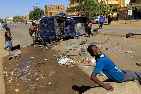 Children play near a police car flipped over and damaged by mourners near the home of a demonstrator who died of a gunshot wound sustained during anti-government protests in Khartoum, Sudan January 18, 2019. REUTERS/Mohamed Nureldin Abdallah