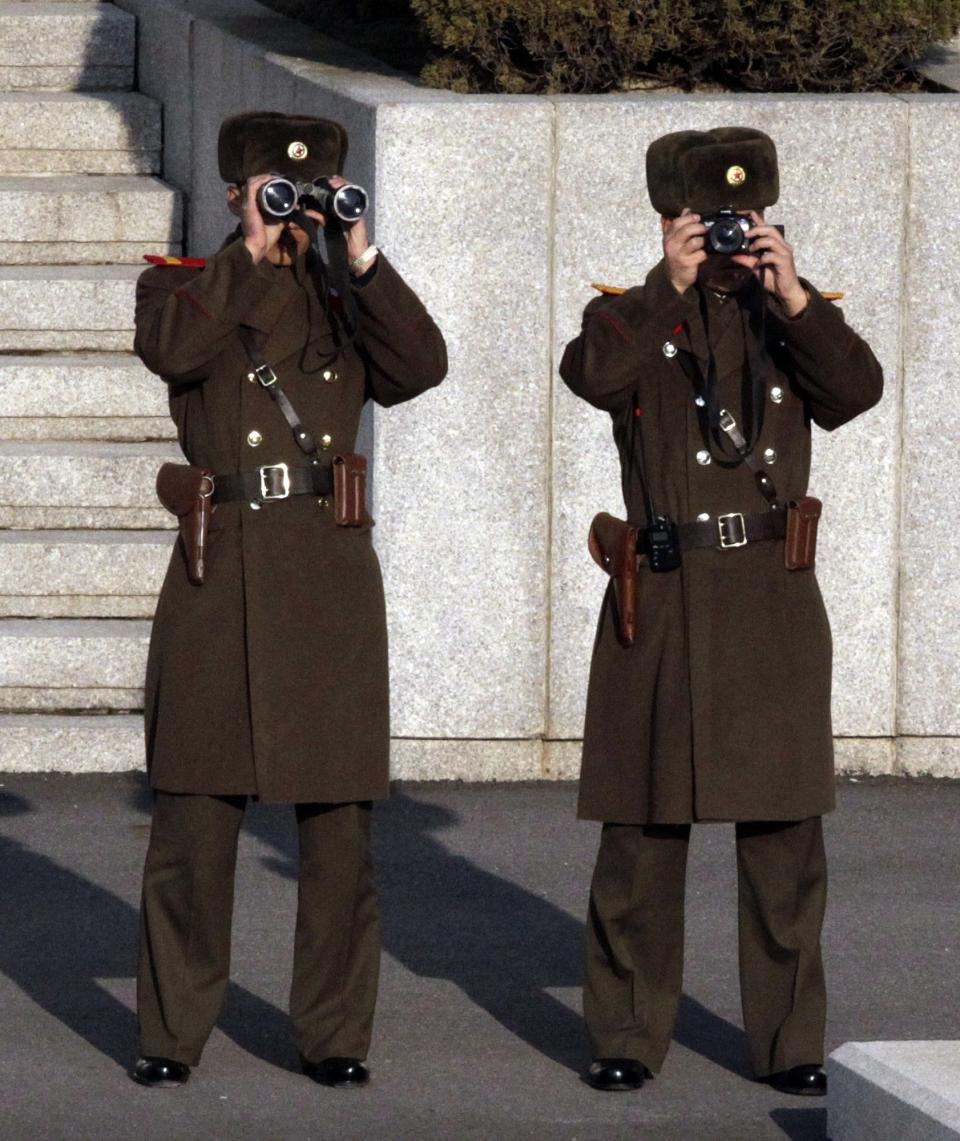 A North Korean soldier (L) looks through binoculars while another soldier takes a photo, as U.S. Vice President Joe Biden visits at the border village of Panmunjom at the Demilitarized Zone (DMZ), the military border separating the two Koreas, December 7, 2013. (REUTERS/Lee Jin-man/Pool)