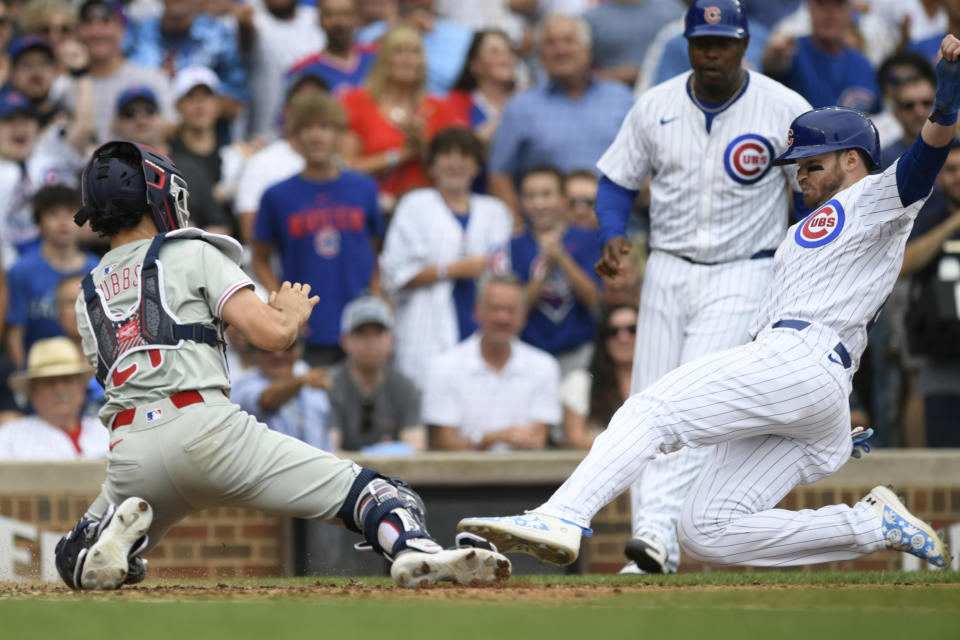 Chicago Cubs' Ian Happ,, right, slides toward home plate before being tagged out by Philadelphia Phillies catcher Garrett Stubbs, left, during the seventh inning of a baseball game Thursday, July 4, 2024, in Chicago. (AP Photo/Paul Beaty)