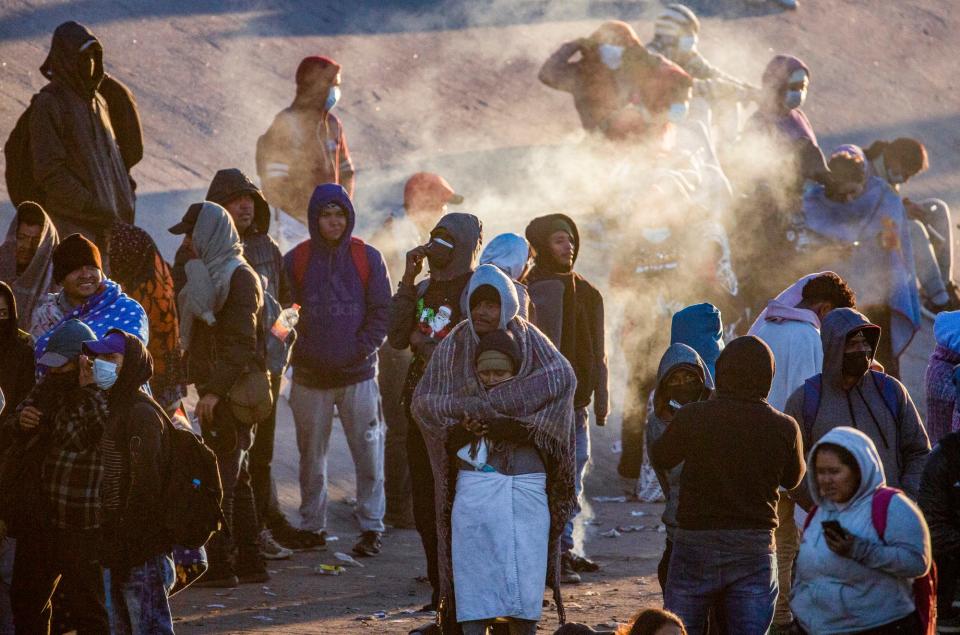 Migrants are photographed as the sun rises. The migrants had spent the night in the north embankment of the Rio Grande after crossing en mass on Sunday, Dec. 11, 2022.