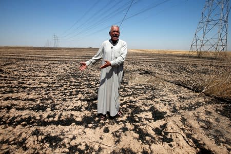 Farmer reacts on his field, which was burned by fire, in al-Hamdaniya