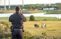 A French gendarme films migrants trying to enter the Eurotunnel in Coquelles near Calais, northern France, on July 31, 2015