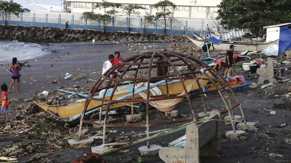 Residents walks beside an outrigger and playground equipment that were damaged by Typhoon Phanfone along a coastline in Ormoc city, central Philippines on Thursday Dec. 26, 2019. The typhoon left over a dozen dead and many homeless. (AP Photo)