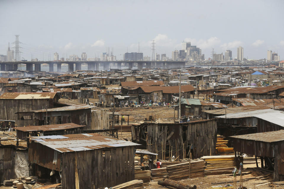 FILE - People in a slum work in a saw mill with downtown in the distance in Lagos, Nigeria, Tuesday May 12, 2020. Dim Coumou, a climate professor at Vrije Universiteit Amsterdam, said the combination of growth in African cities and climate change presents a serious risk. “As the population increases in these megacities, you have more buildings, more concrete and an increased heat-island effect, making the heat waves worse,” Coumou says. “I think it’s a dangerous combination.” (AP Photo/Sunday Alamba, File)