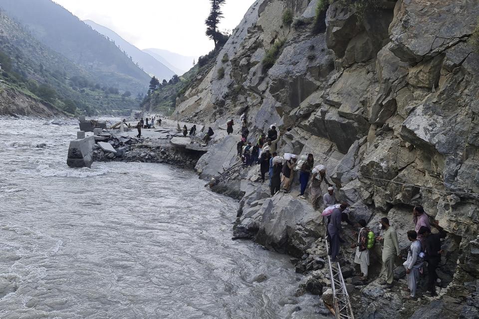 FILE - Local residents cross a portion of a road destroyed by floodwaters in Kalam Valley in northern Pakistan, Sept. 4, 2022. The flooding in Pakistan killed at least 1,700 people, destroyed millions of homes, wiped out swathes of farmland, and caused billions of dollars in economic losses. In Khyber Pakhtunkhwa, residents had to rely on contaminated water, so now authorities are taking steps to prepare for the next disaster. (AP Photo/Sherin Zada, File)