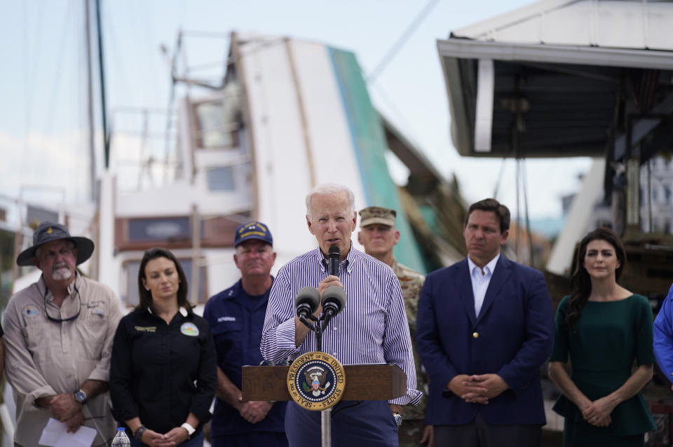 FILE - President Joe Biden speaks after touring an area impacted by Hurricane Ian on Oct. 5, 2022, in Fort Myers Beach, Fla. Florida Gov. Ron DeSantis, second from right, and his wife Casey DeSantis listen. Whenever the president travels, a special bullet-resistant lectern called the “blue goose,” or its smaller cousin “the falcon,” is in tow. Lately, Biden is rendering them all but obsolete as he increasingly reaches for a hand-held microphone instead. Those who know him best say the mic swap makes Biden a much more natural speaker. (AP Photo/Evan Vucci, File)