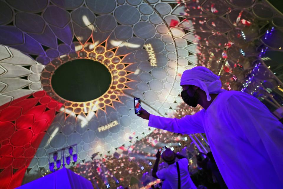 FILE - A man takes selfie under the dome of Al Wasl Plaza coloured in French national flag, during a French ceremonial day at the Dubai Expo 2020 in Dubai, United Arab Emirates, Oct. 2, 2021. Intent on making a flawless impression as the first host of the world’s fair in the Middle East, Dubai has spent over $7 billion on pristine fairgrounds and jubilant festivities. But propping up the elaborate fair is the United Arab Emirates’ contentious labor system that long has drawn accusations of mistreatment. (AP Photo/Kamran Jebreili, File)