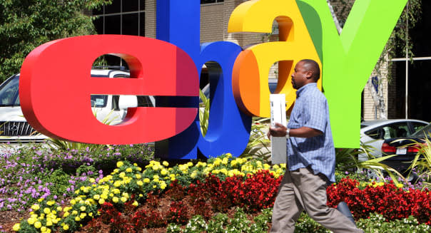 ebay headquarters in San Jose California. An employee carries a computer in front of the ebay logo